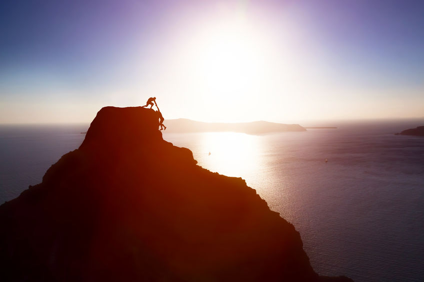 Climber giving hand and helping his friend to reach the top of the mountain. Help, support Climber giving hand and helping his friend to reach the top of the mountain. Help, support, assistance, teamwork in a dangerous situation concepts